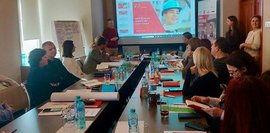 Eine Gruppe von Männern und Frauen in formeller Kleidung versammelt sich in einem modernen Raum mit Holzdekor für ein Gruppenfoto.