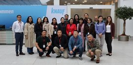Eine Gruppe von ca. 15 Personen, hauptsächlich Frauen, steht vor einem Empfangstresen. Sie lächeln in die Kamera. Ein Knauf-Logo ist im Hintergrund sichtbar. Das Foto vermittelt einen freundlichen und professionellen Eindruck.