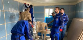 Im Training zur Innenraum-Wärmedämmung bringen Teilnehmende in blauer Arbeitskleidung Dämmplatten