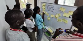 Senegalesische Studierende stehen vor einem Whiteboard und diskutieren. 