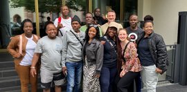 Gruppenfoto vor dem Hotel mit Teilnehmer der Delegationsreise Eine Gruppe von Menschen steht vor dem Eingang eines Hotels in drei Reihen und macht ein fröhliches Gruppenfoto