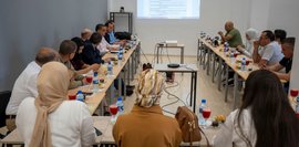 Präsentation der Ergebnisse der Bedarfsanalyse Projektpartner und lokaler bbw-Experte sitzen um einen Tisch und blicken auf die Powerpoint-Präsentation der Bedarfsanalyse.