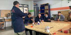 Das Foto zeigt den Ausbilder der Kurzqualifikation Wartung der Ausrüstung, der den Schülern zeigt, wie eine Steckdose installiert wird. 