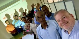 Gruppenfoto der Teilnehmer*innen des Planungsworkshops 2024. Mehrere Menschen lächeln in die Kamera, ein Mann macht ein Selfie. Die Szenerie ist ein Konferenzraum. Ein Projektor zeigt "Bayarian Ethiopian Youth Employment Project".