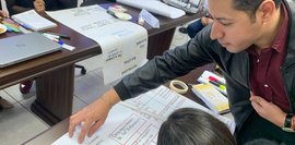 Das Bild zeigt zwei Personen, die an einer Flipchart-Präsentation arbeiten.