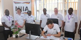 Einrichtung des NJIA-Projektbüros am KCNP Mehrere Mitglieder des NJIA-Projektteams stehen gemeinsam in einem Büro am Kenya Coast National Polytechnic. Eine Person sitzt am Schreibtisch und unterschreibt ein Dokument. Im Hintergrund ist ein NJIA-Roll-up zu sehen. Das Bild zeigt die Einrichtung und Nutzung des lokalen Projektbüros sowie die Zusammenarbeit zwischen bbw gGmbH, KCNP und weiteren Projektpartnern.