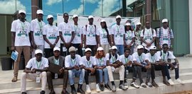 Die 20 Studierenden der senegalesischen Partnerhochschule stehen und sitzen in 2 Reihen vor einem Gebäude.  