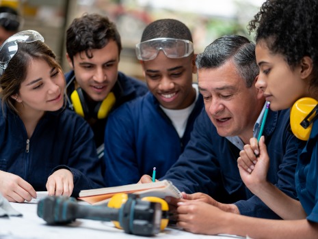 Interessierte Auszubildende hören ihrem Ausbilder aufmerksam zu. Konzentration und Freude am Lernen im Fokus.
