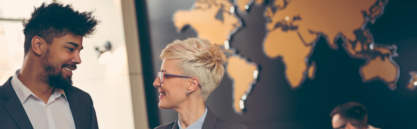 Zwei Kollegen besprechen sich vor einer Weltkarte