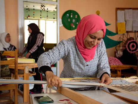 Das Bild zeigt eine junge Frau am Webstuhl