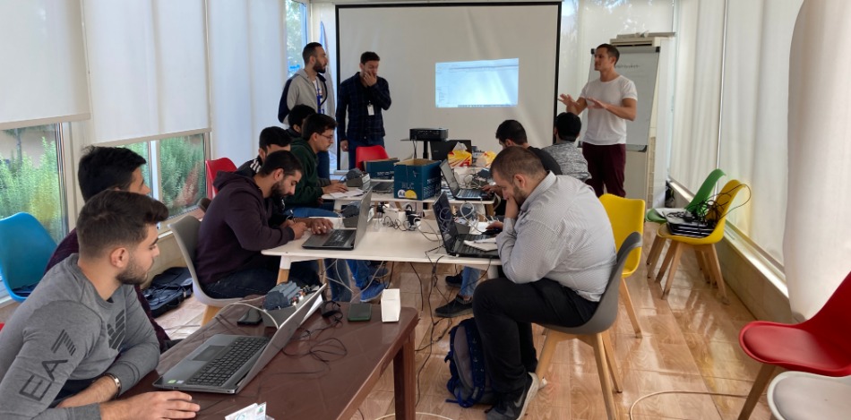 Ein Trainer erklärt PLC-Programmierung vor einer Gruppe Teilnehmender. Die Schulung findet in einem modern ausgestatteten Seminarraum statt.