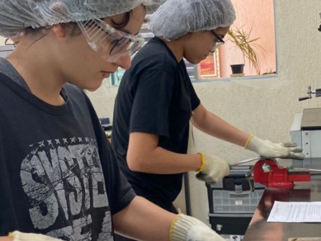 Zwei Mädchen feilen an einer Erkennungsmarke aus Metall