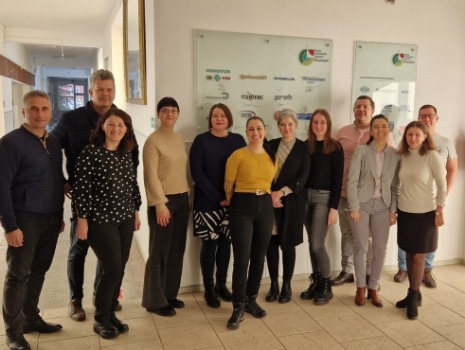 Die beteiligten Projektpartner besichtigen eine Ausbildungswerkstatt und schauen sich Werkstücke aus der CNC Maschine im Hintergrund an. 