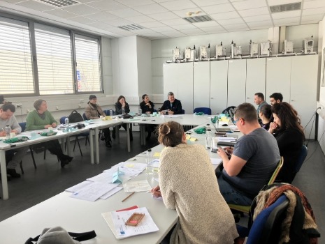 Die beteiligten Projektpartner sitzen an Tischen in U Form und diskutieren gemeinsam. 