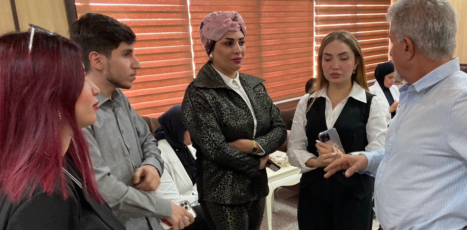 Angeregte Diskussion beim Planungsworkshop in Erbil: Fünf Erwachsene, drei Frauen und zwei Männer, unterhalten sich. Der Hintergrund zeigt ein Büro mit Vorhängen.