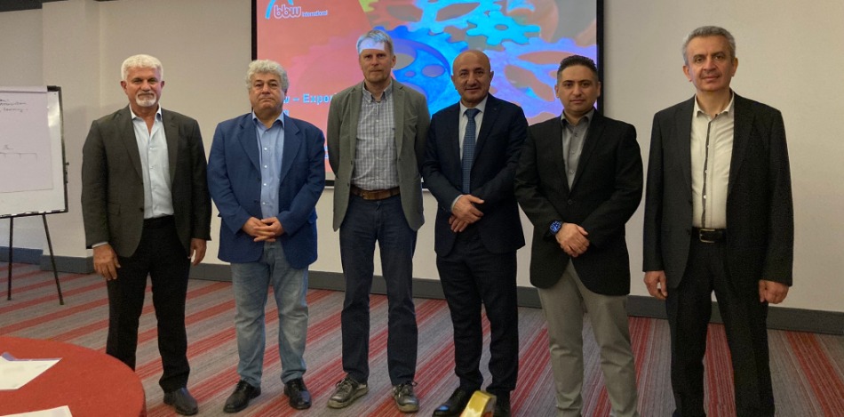 Gruppenfoto von sechs Männern in Anzügen beim bbw International Planungsworkshop in Erbil. Sie stehen vor einer Leinwand.