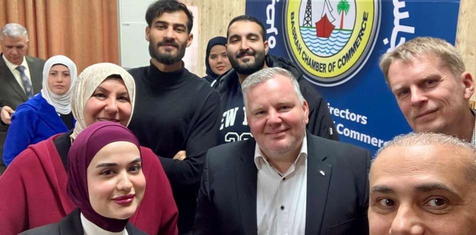Gruppenfoto vom Basra Planungsworkshop 2025. Diverse Personen stehen vor dem Logo der Basra Handelskammer. Lächelnde Gesichter, freundliche Atmosphäre.