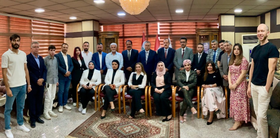 Gruppenfoto von ca. 25 Personen, größtenteils Männer und Frauen in Businesskleidung, bei einem Workshop zu Herausforderungen für KMU. Der Raum ist elegant eingerichtet mit Teppich und Kronleuchter.