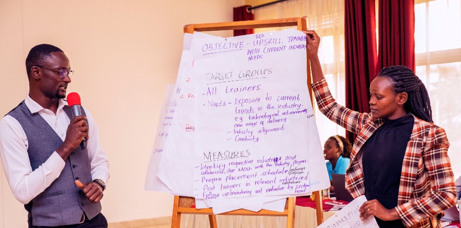 Eine Frau hält ein Plakat hoch, während ein Mann mit Mikrofon die Inhalte erläutert.