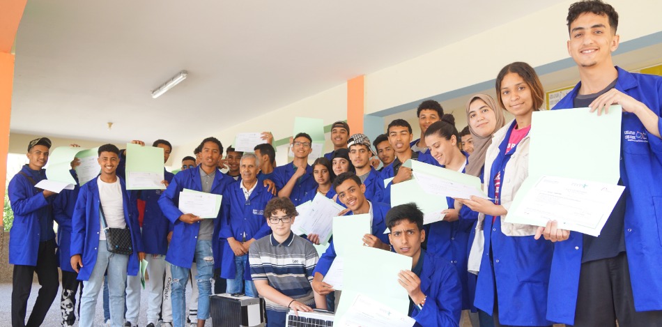 Das Bild zeigt eine Gruppe von Green Bina Maroc Absolvent*innen und Ausbilder*innen, die stolz ihre Zertifikate präsentieren. Die Jugendlichen haben gerade eine Schulung im Bereich erneuerbarer Energien mit einem bbw Experten absolviert.