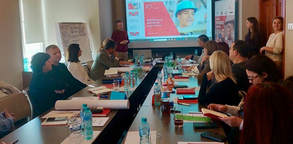 Eine Gruppe von Männern und Frauen in formeller Kleidung versammelt sich in einem modernen Raum mit Holzdekor für ein Gruppenfoto.