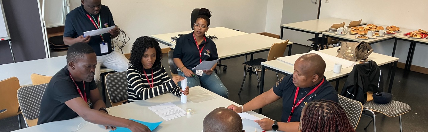 Workshop zum Thema Begleitung von Jugendlichen beim bfz Bamberg Sieben Personen sitzen um einen Tisch und diskutieren die Lösung einer Aufgabe.