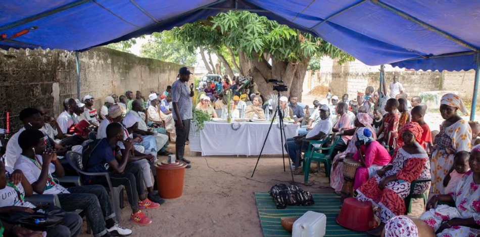 Eine große Gruppe von Menschen sitzt zusammen und eine Person in der Mitte spricht. 