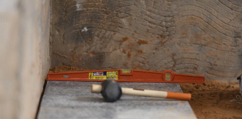 Ausnivellierte Fliesen. Eine Wasserwaage und ein Gummihammer liegen auf den Fliesen.