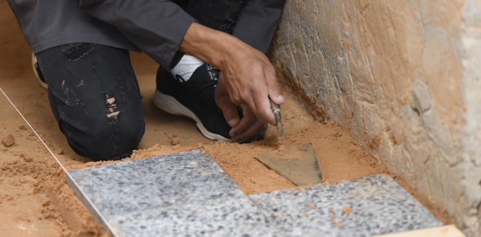 Ein Schüler setzt Fliese an Fliese. Er hält dabei eine Maurerkelle.