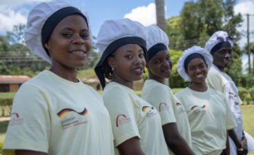 Das Bild zeigt eine Gruppe von Menschen in Kochkleidung, die gemeinsam an einem Berufsbildungsprogramm teilnehmen.