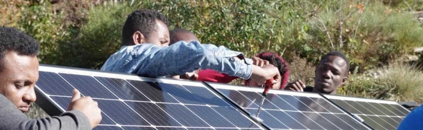 Das Bild zeigt afrikanische Lehrkräfte, die gemeinsam eine PV-Inselanlage aufbauen. In Zusammenarbeit setzen sie theoretisches Wissen in die Praxis um, um erneuerbare Energien nachhaltig zu nutzen und weiterzuvermitteln.